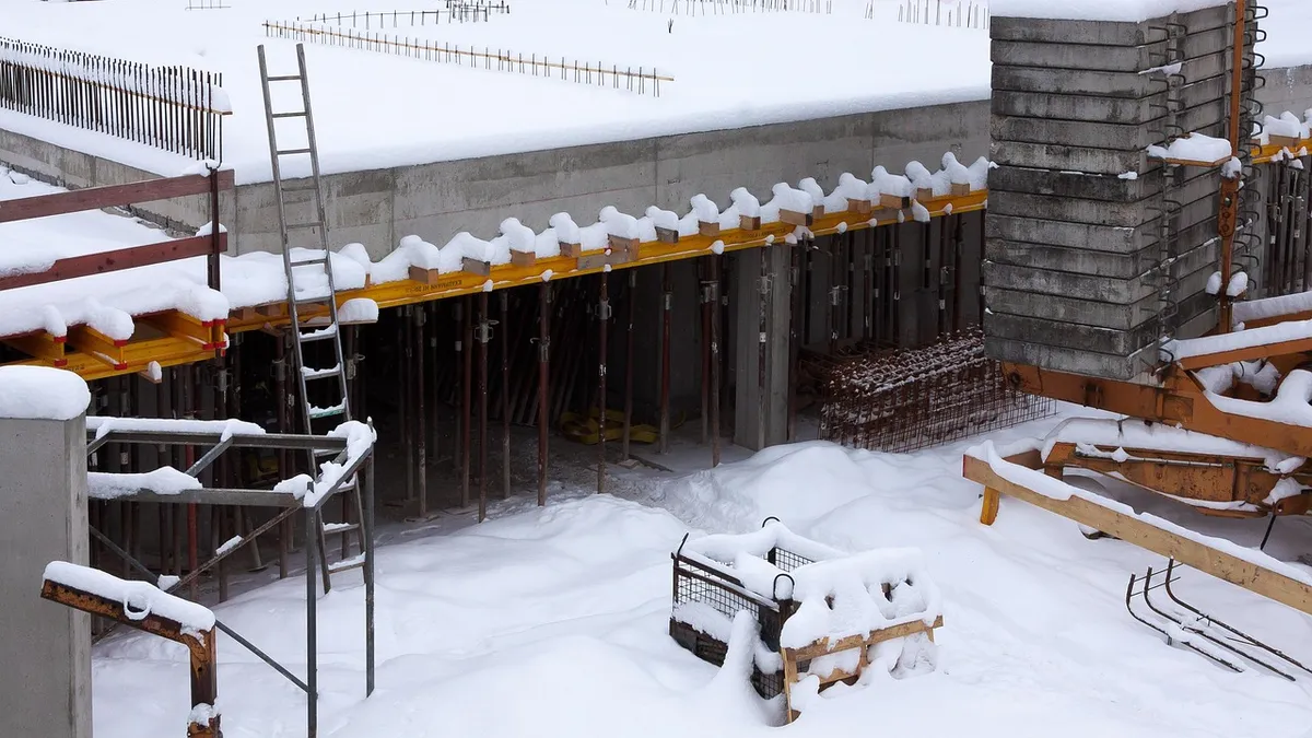 A snow-covered concrete slab with formwork props and rebar