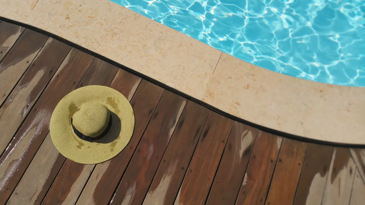 A pool edge and a straw hat on the deck