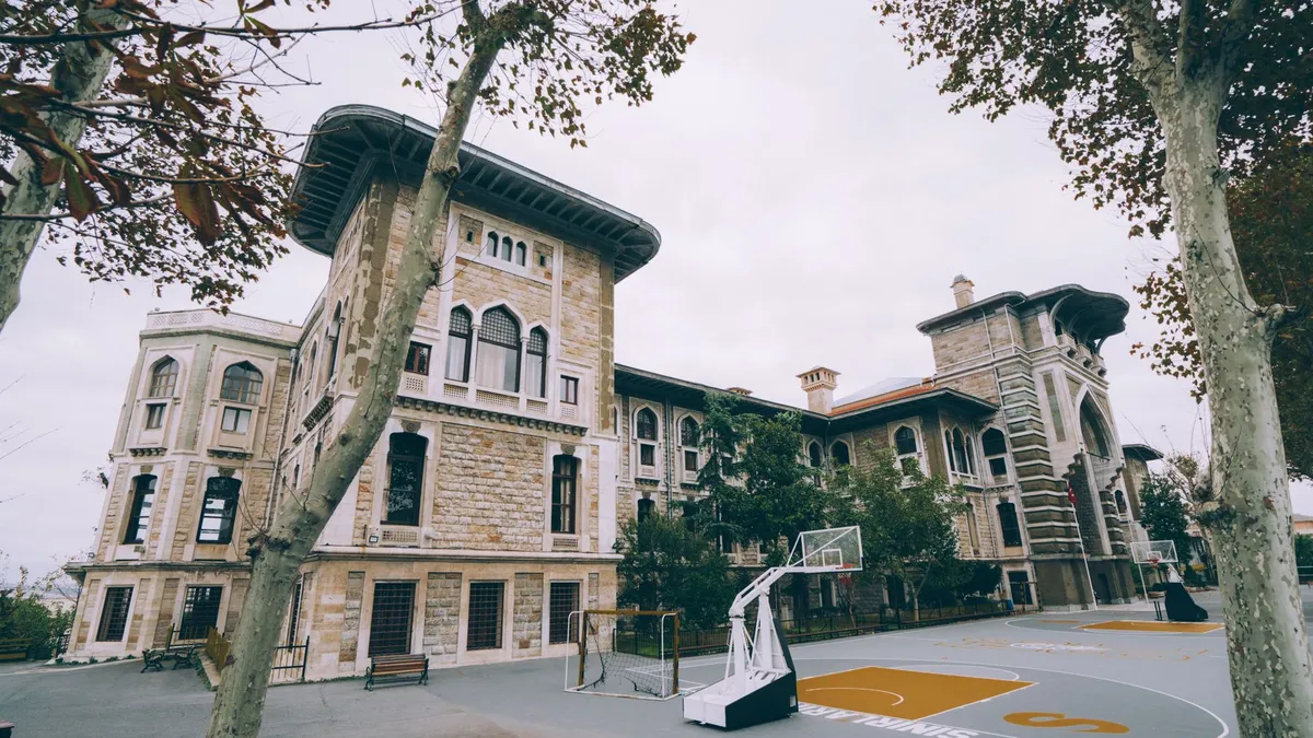 A basketball hoop and court in front of a historic school building